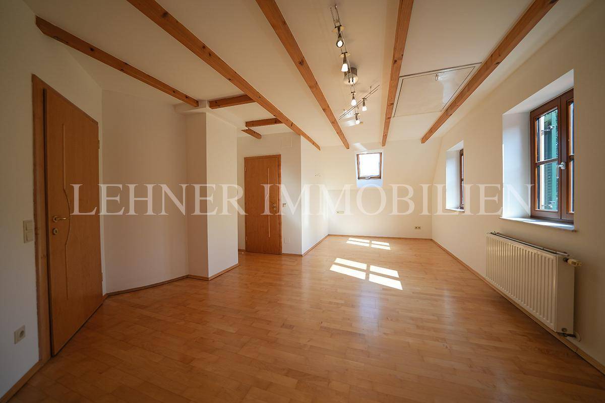 Helles Zimmer im Dachgeschoss mit Holzboden, Dachfenster und Blick ins Grüne.