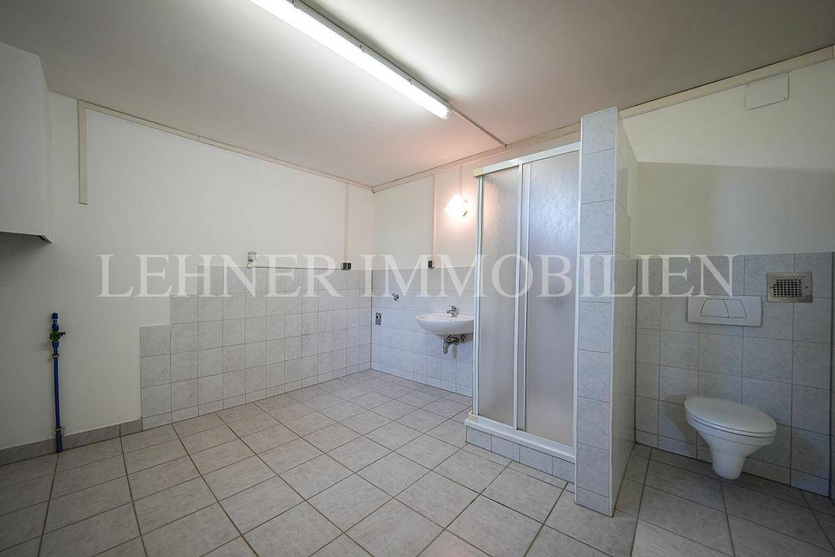 Einfaches Badezimmer im Keller mit Dusche, WC und Fliesenboden.