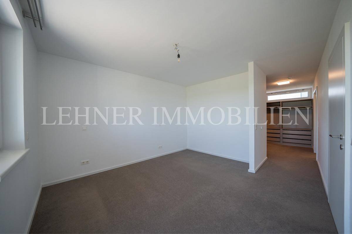 Helles Schlafzimmer mit Teppichboden und angrenzendem Bereich, ideal für einen begehbaren Kleiderschrank.