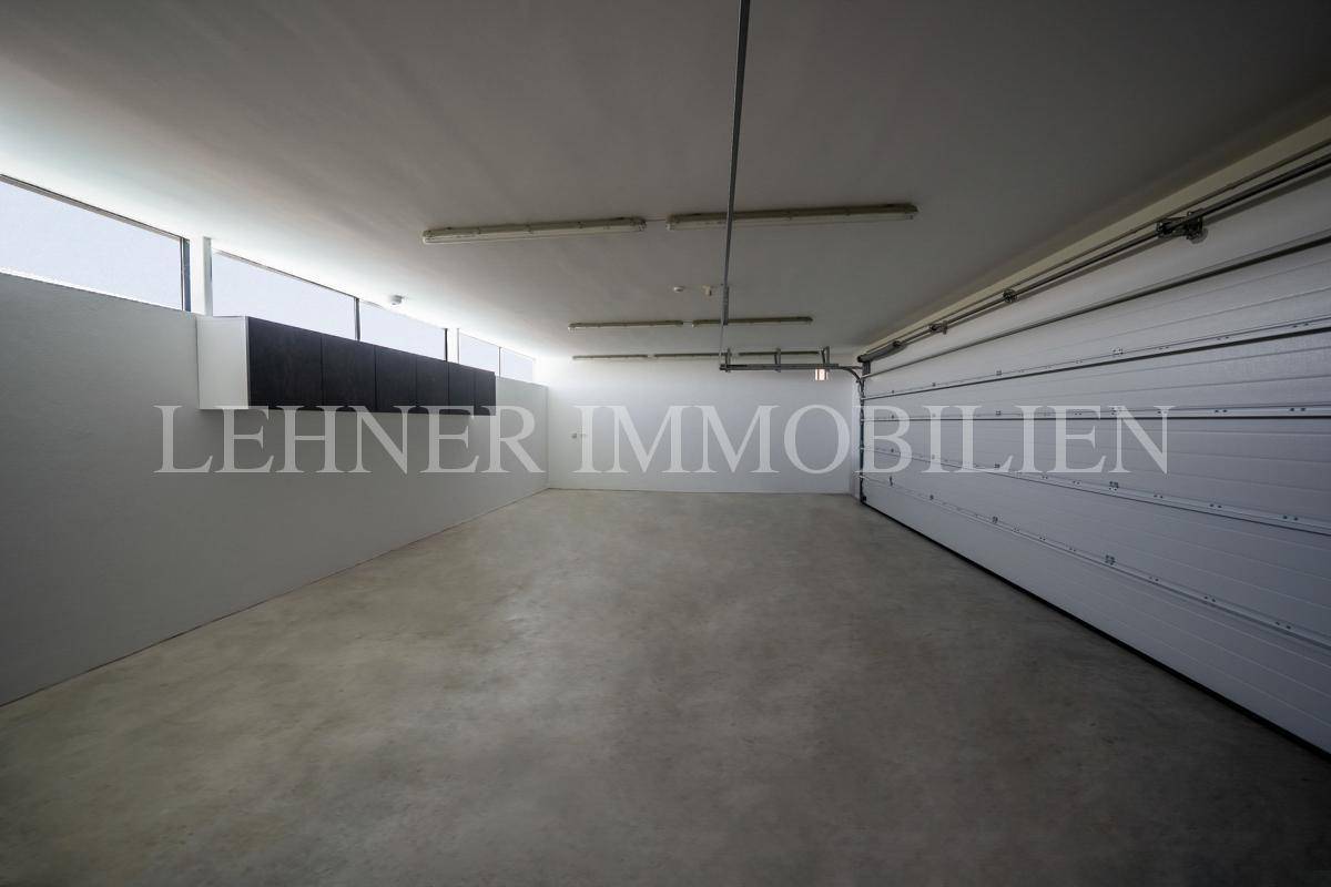 Geräumige Garage mit Betonboden und großem Rolltor, bietet Platz für mehrere Fahrzeuge.