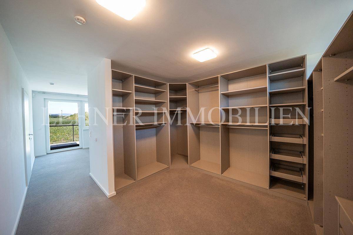 Großer begehbarer Kleiderschrank mit umfangreichen Regalen und Stauraum, hell beleuchtet.