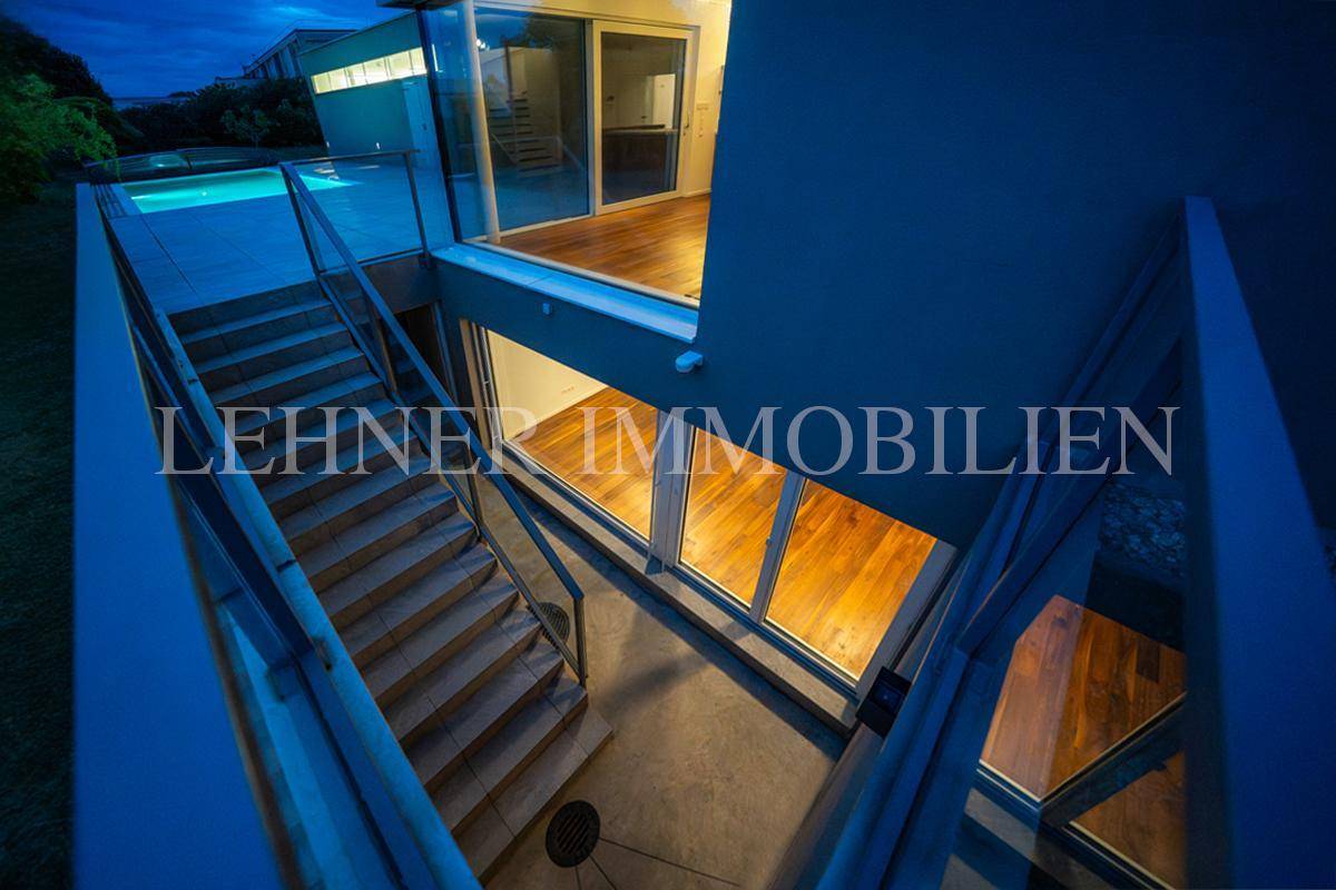Innenansicht mit moderner Treppe und Holzfußboden, die verschiedene Ebenen des Hauses verbindet.