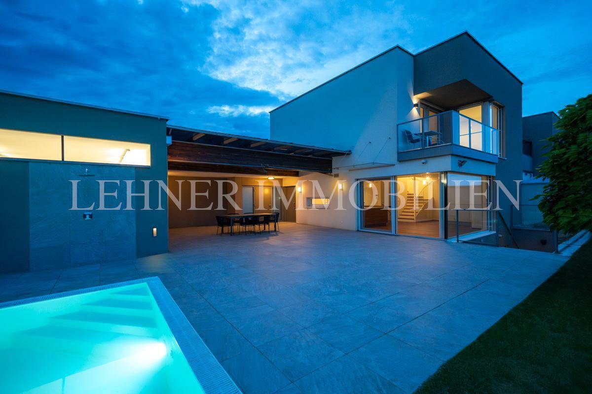 Beeindruckende Nachtansicht der modernen Villa mit beleuchtetem Pool und weitläufiger Terrasse.