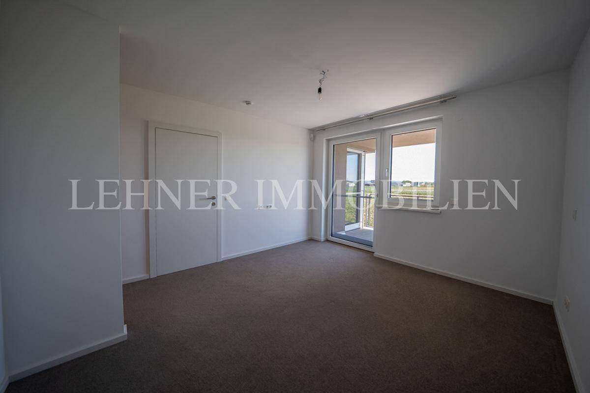 Geräumiges Schlafzimmer mit Teppichboden und direktem Zugang zum sonnigen Balkon.