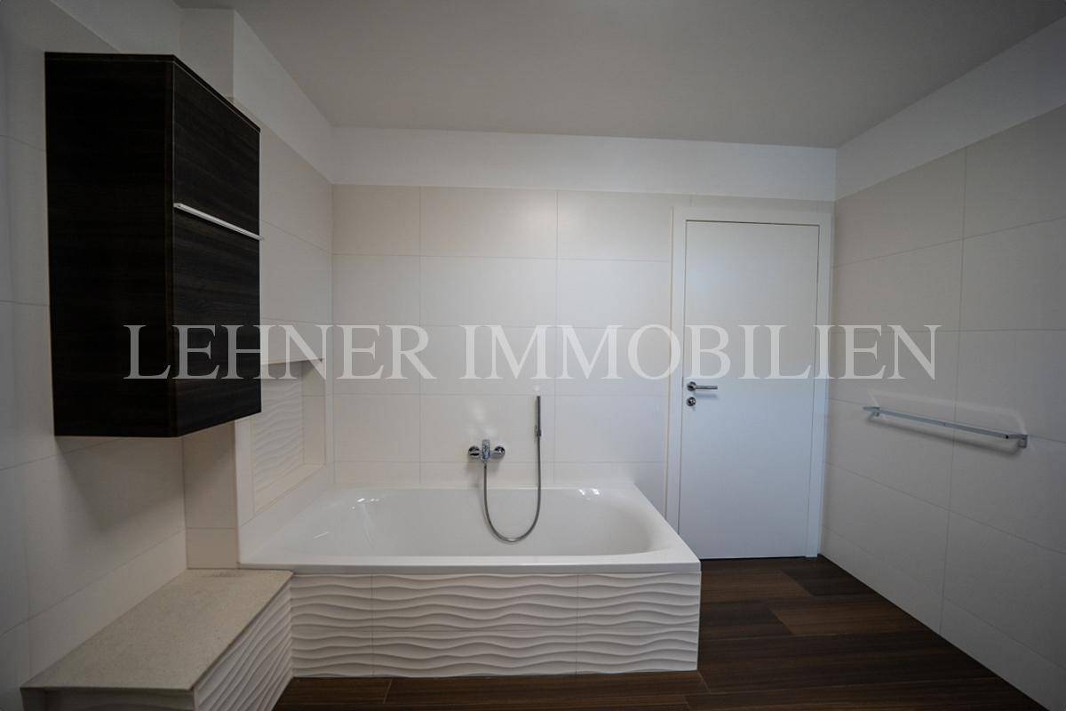 Badezimmer mit Badewanne, dunklem Hängeschrank und modernen Fliesen, die eine ruhige Atmosphäre schaffen.