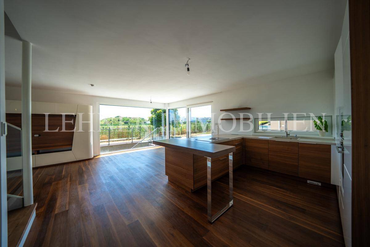 Geräumiger offener Wohn- und Küchenbereich mit dunklem Holzboden und Zugang zur Terrasse.