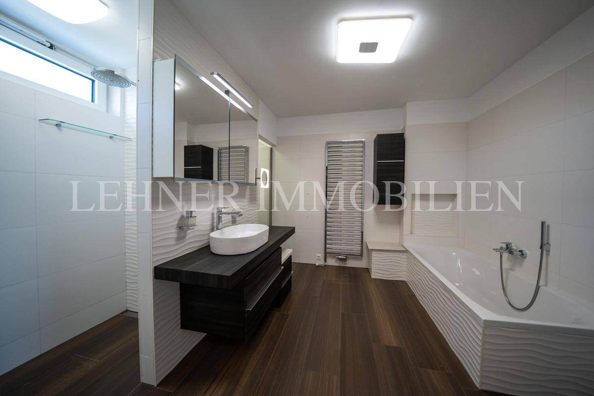 Elegantes Badezimmer mit Badewanne, modernem Waschtisch und separatem Duschbereich.