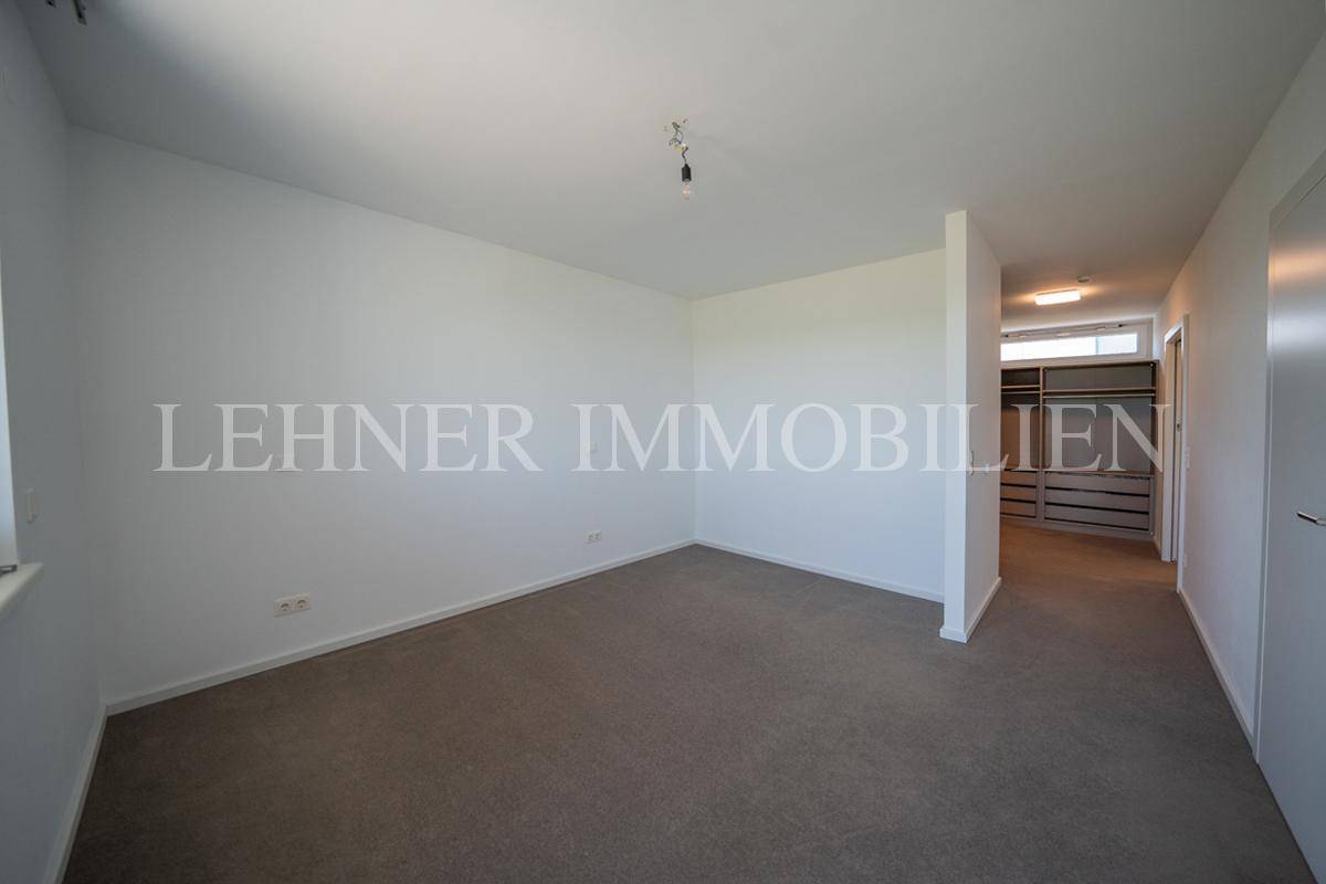 Geräumiges Schlafzimmer mit Teppichboden und vorbereitetem Bereich für einen begehbaren Kleiderschrank.