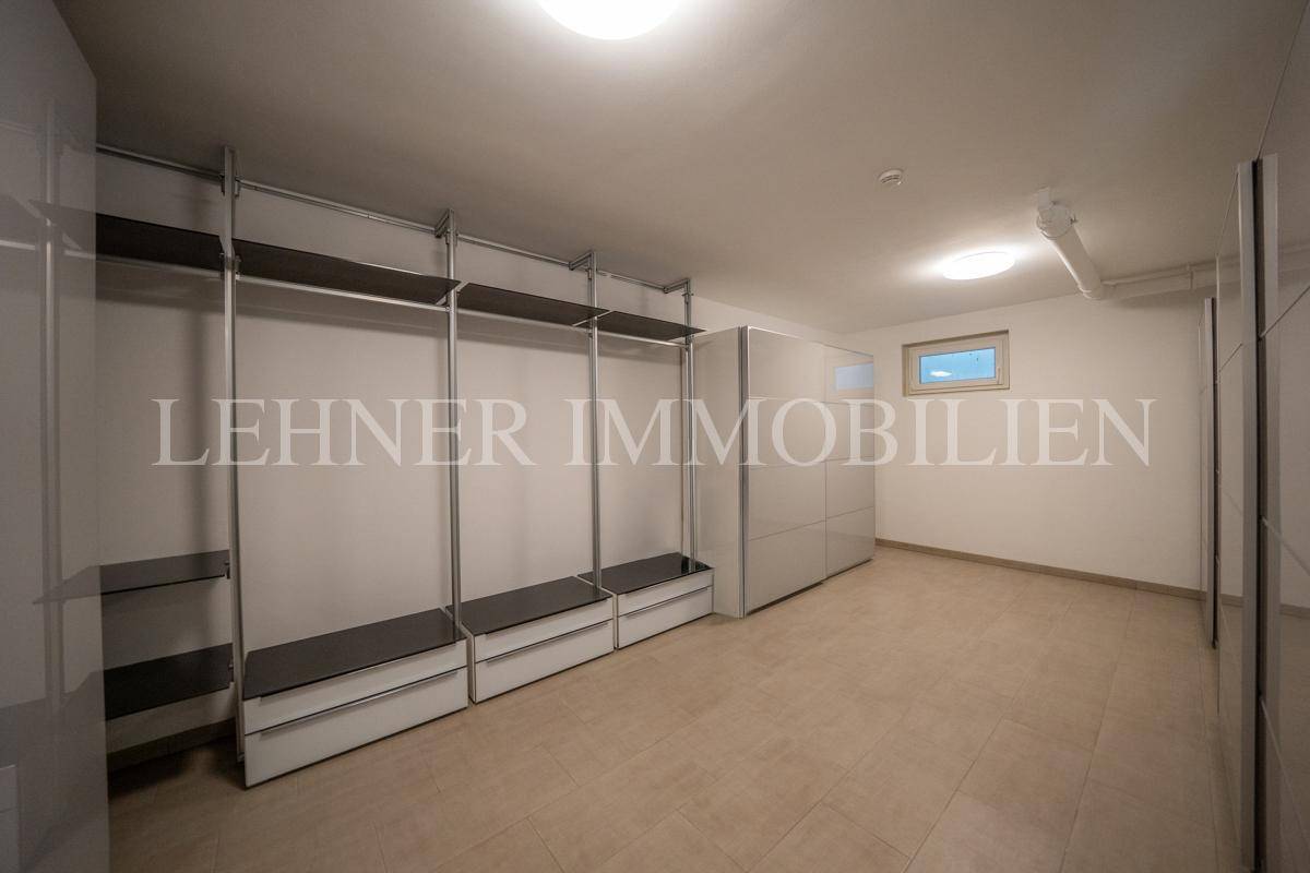 Geräumiger begehbarer Kleiderschrank mit modularen Regalsystemen und kleinem Fenster.