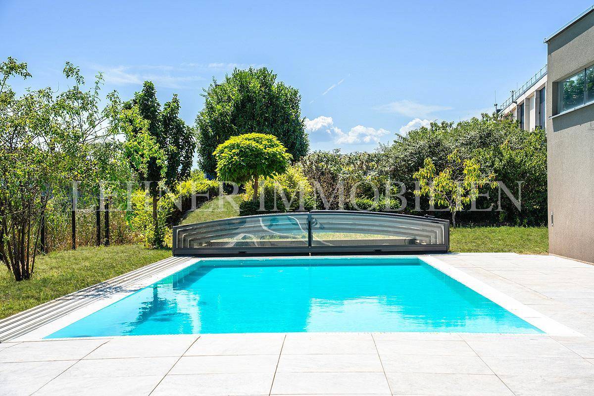 Gepflegter Pool mit Abdeckung, umgeben von üppigem Grün und Bäumen, ideal für Entspannung.