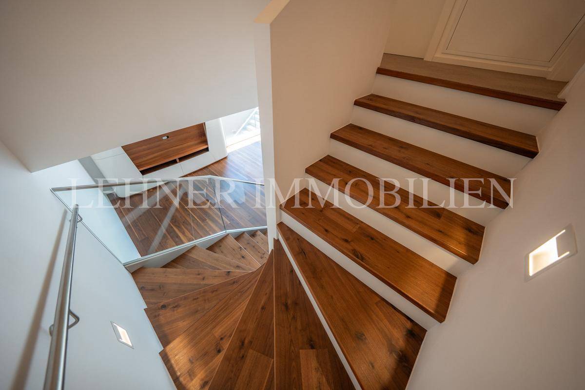 Elegante Holztreppe mit Glasgeländer, von oben fotografiert, betont modernes Design.