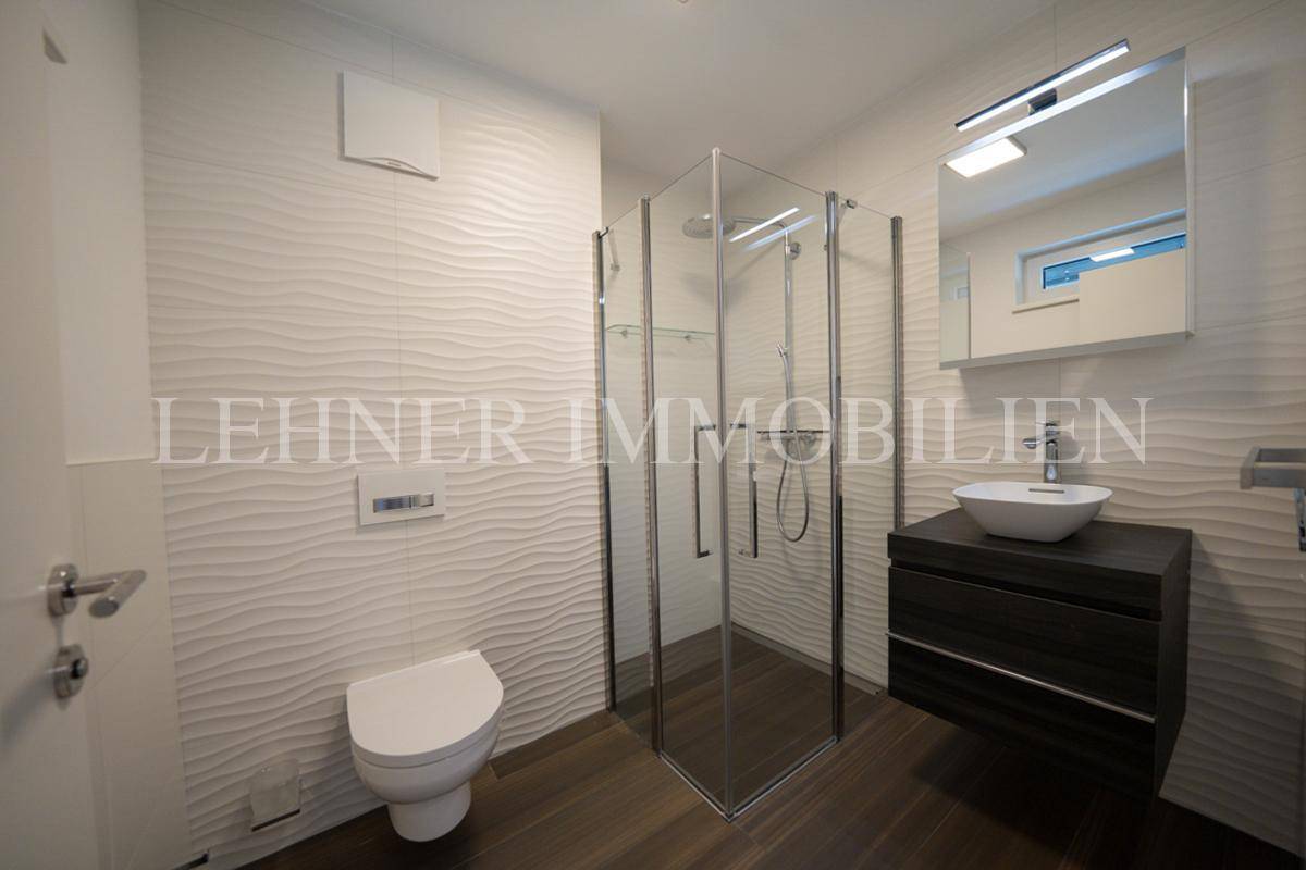 Modernes Badezimmer mit Duschkabine, wandhängendem WC und stilvollem Waschtisch.
