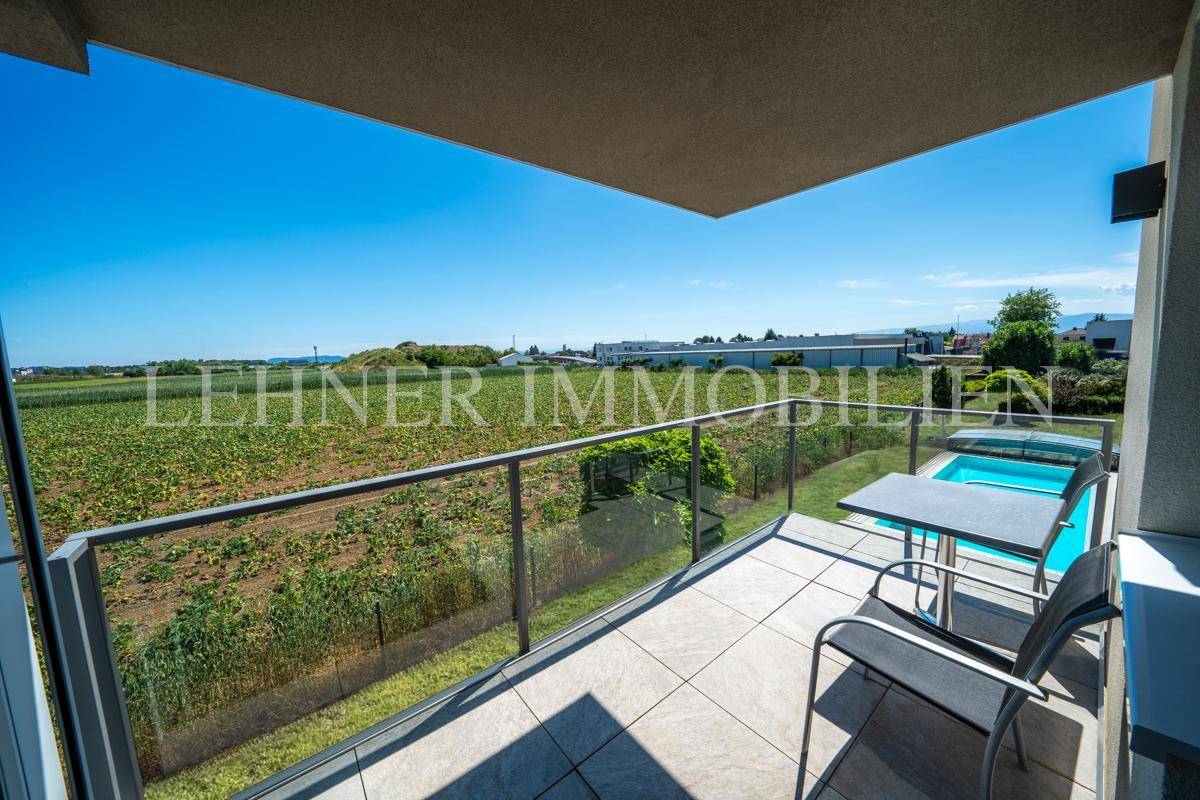 Geräumiger Balkon mit Fliesenboden, Glasgeländer und Sitzgelegenheiten, bietet weite Aussicht.