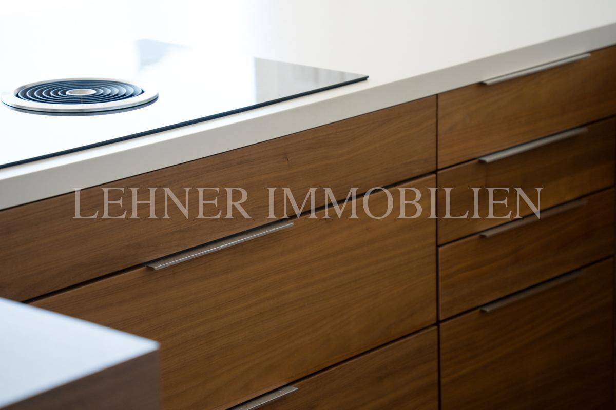 Detailaufnahme der modernen Kücheninsel mit integriertem Kochfeld und eleganten Holzschubladen.