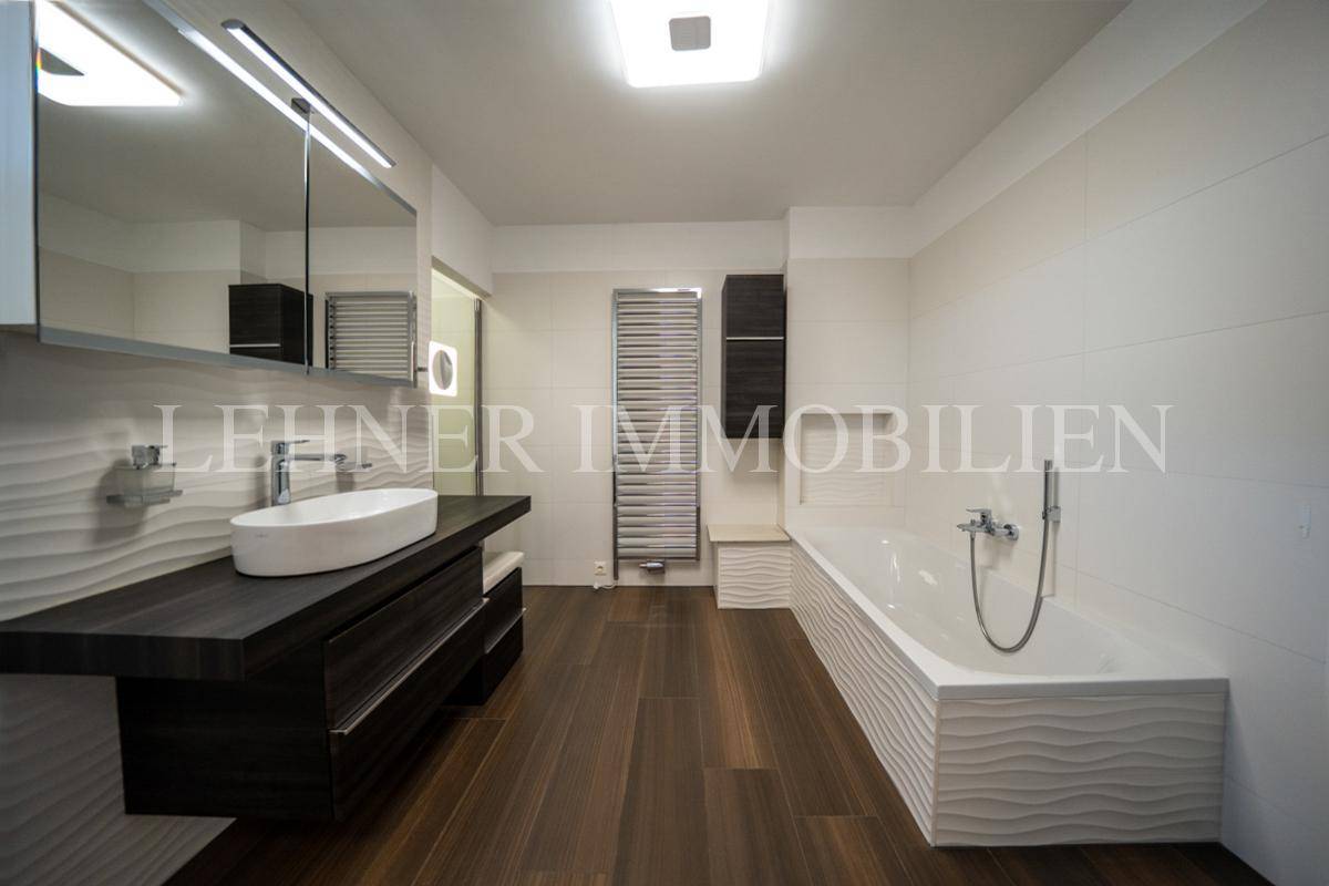 Geräumiges Badezimmer mit Badewanne, Waschtisch und beheiztem Handtuchhalter, modern gestaltet.