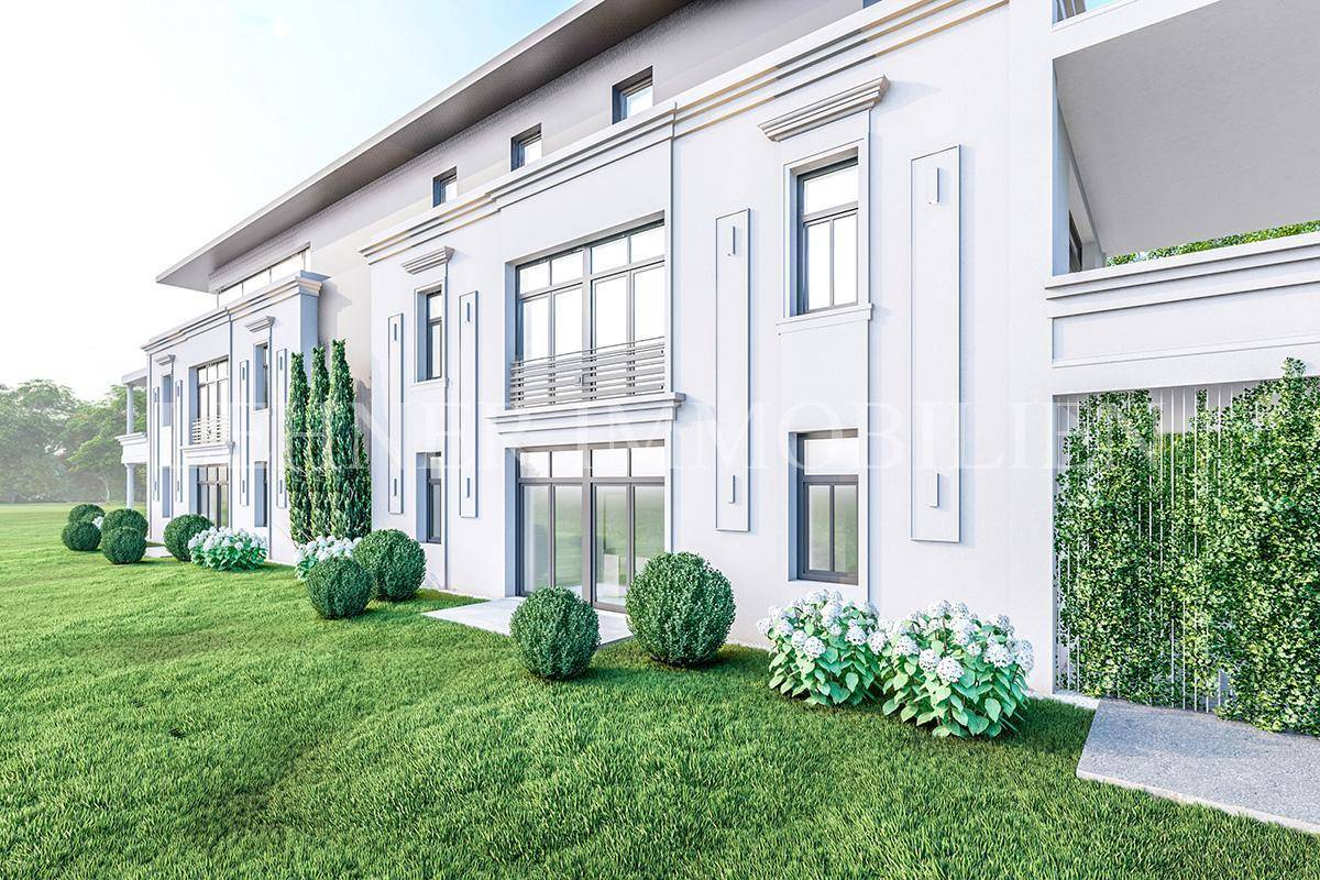 Detailansicht der modernen Fassade einer Villa mit großen Fenstern und gepflegter Hecke.