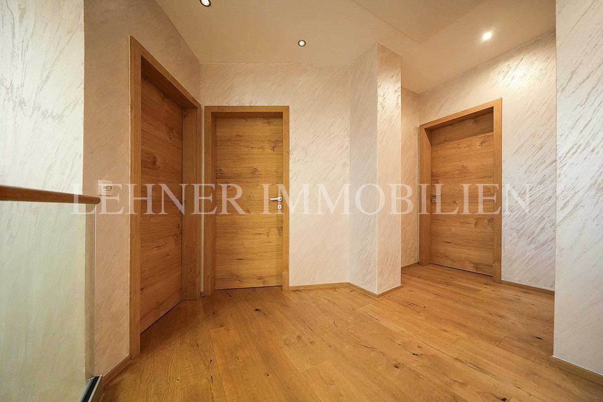 Heller Flur mit Holzfußboden und mehreren modernen Holztüren, die zu den Zimmern führen.
