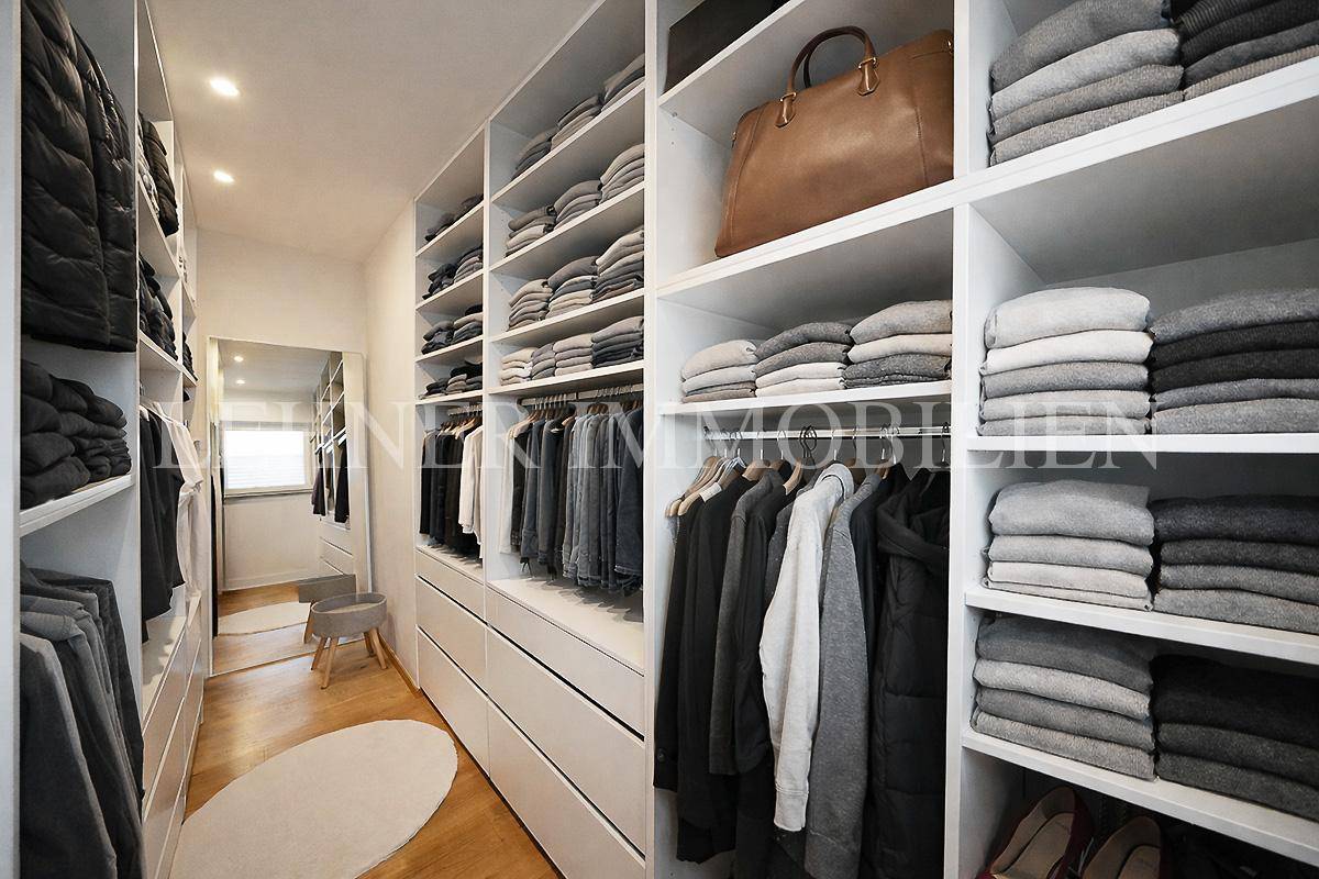 Geräumiger begehbarer Kleiderschrank mit vielen Regalen und Aufbewahrungsmöglichkeiten.