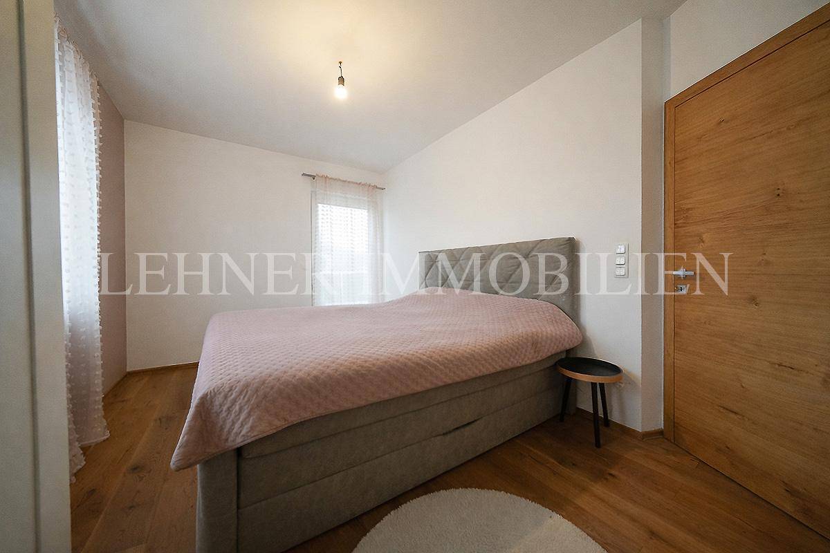 Helles Schlafzimmer mit Holzboden, großem Bett und einem Fenster für natürliche Belichtung.