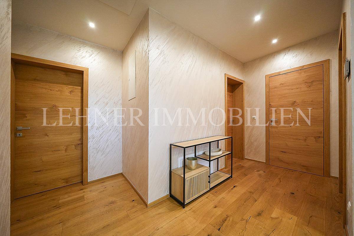 Geräumiger Flur mit Holzfußboden, modernen Holztüren und einem minimalistischen Regal.