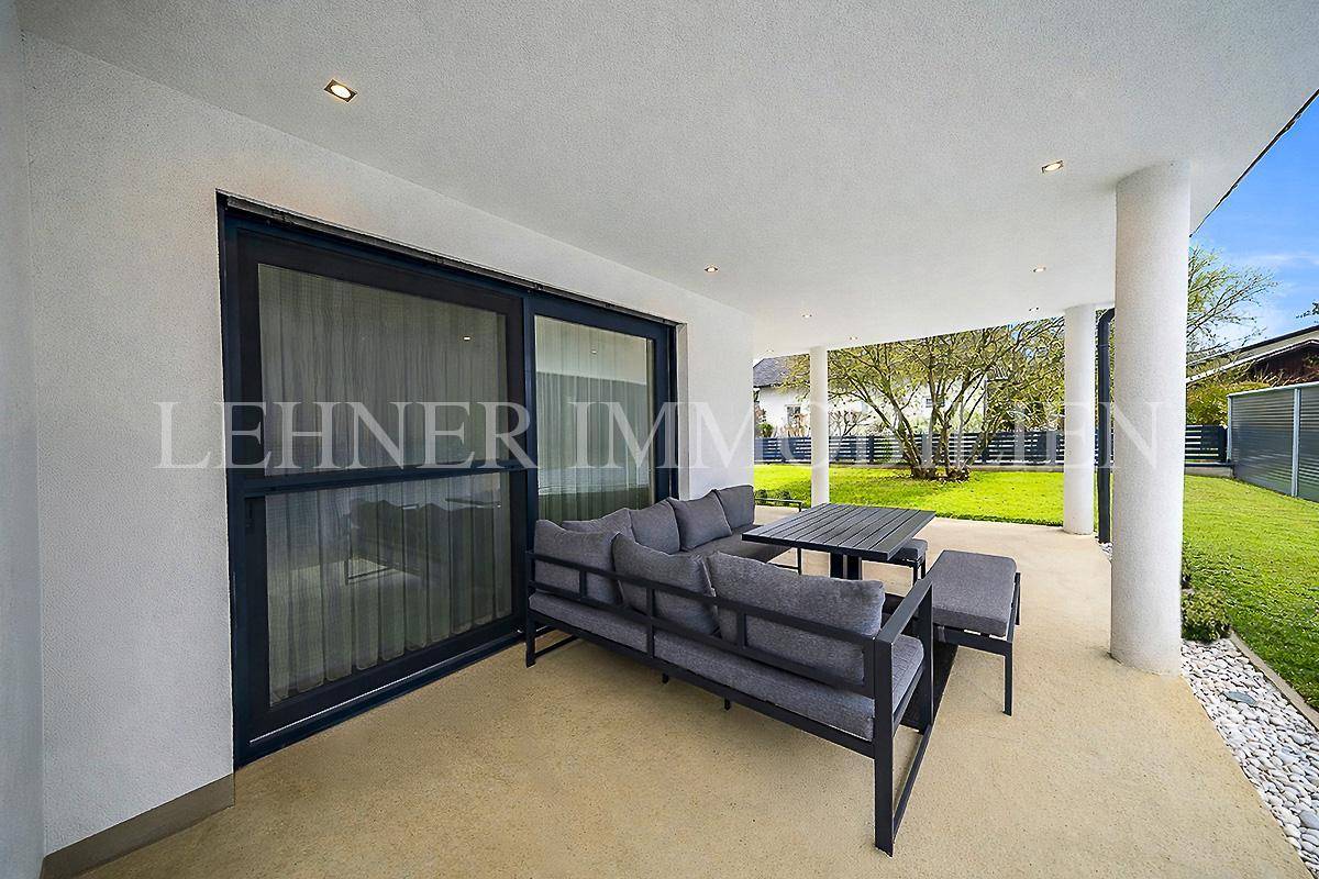 Detailansicht der modernen Lounge-Möbel auf der überdachten Terrasse mit Schiebetüren.