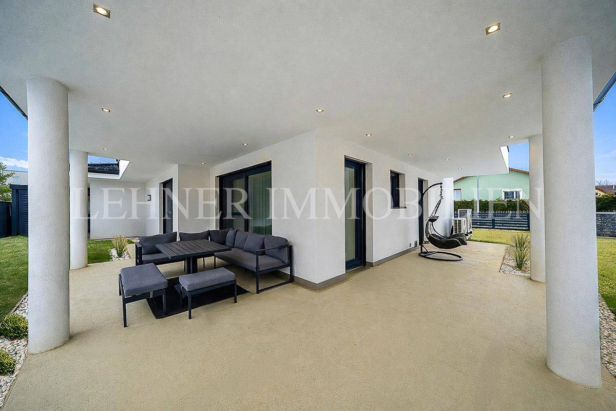 Großzügige überdachte Terrasse mit Lounge-Bereich und einem stilvollen Hängesessel.