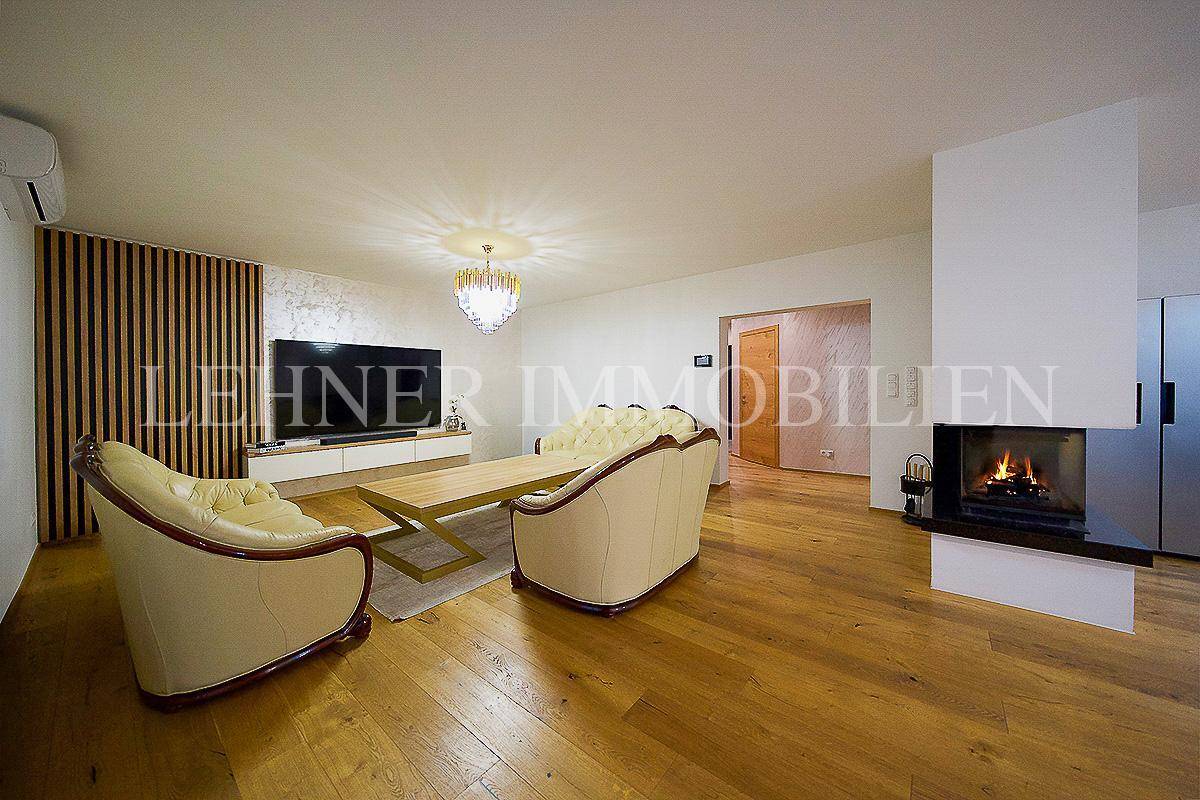 Gemütliches Wohnzimmer mit Kamin, Holzboden, großem Fernseher und bequemen Sofas.