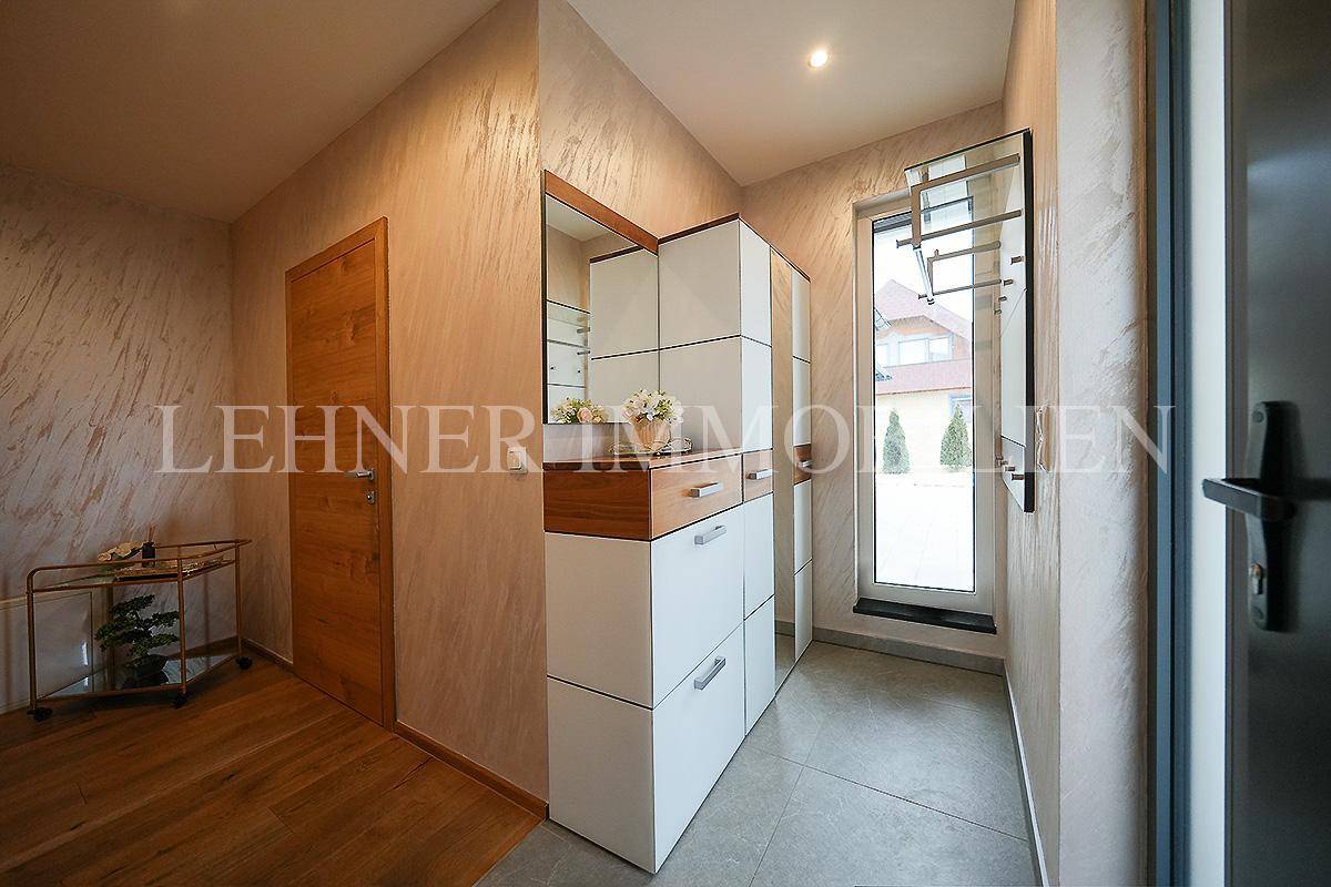 Heller Eingangsbereich mit Garderobe, Spiegel und Fenster.