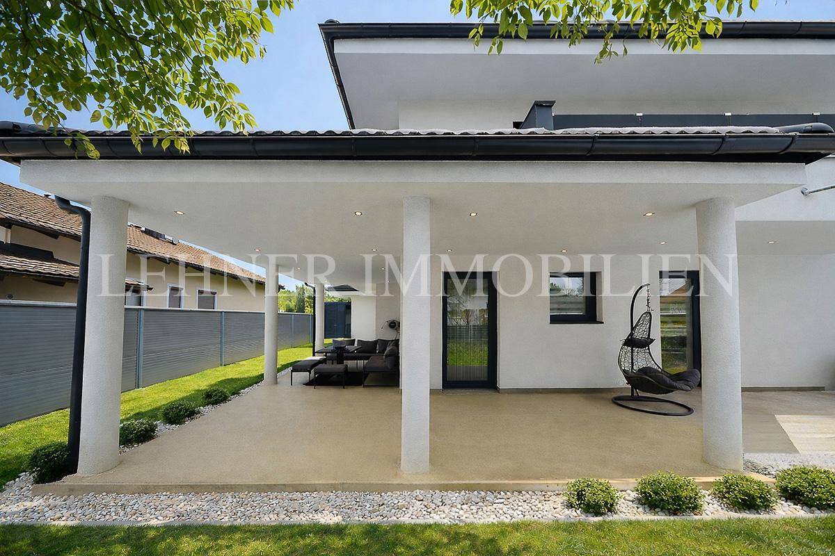 Gemütliche überdachte Terrasse mit modernen Lounge-Möbeln und Hängesessel im Freien.