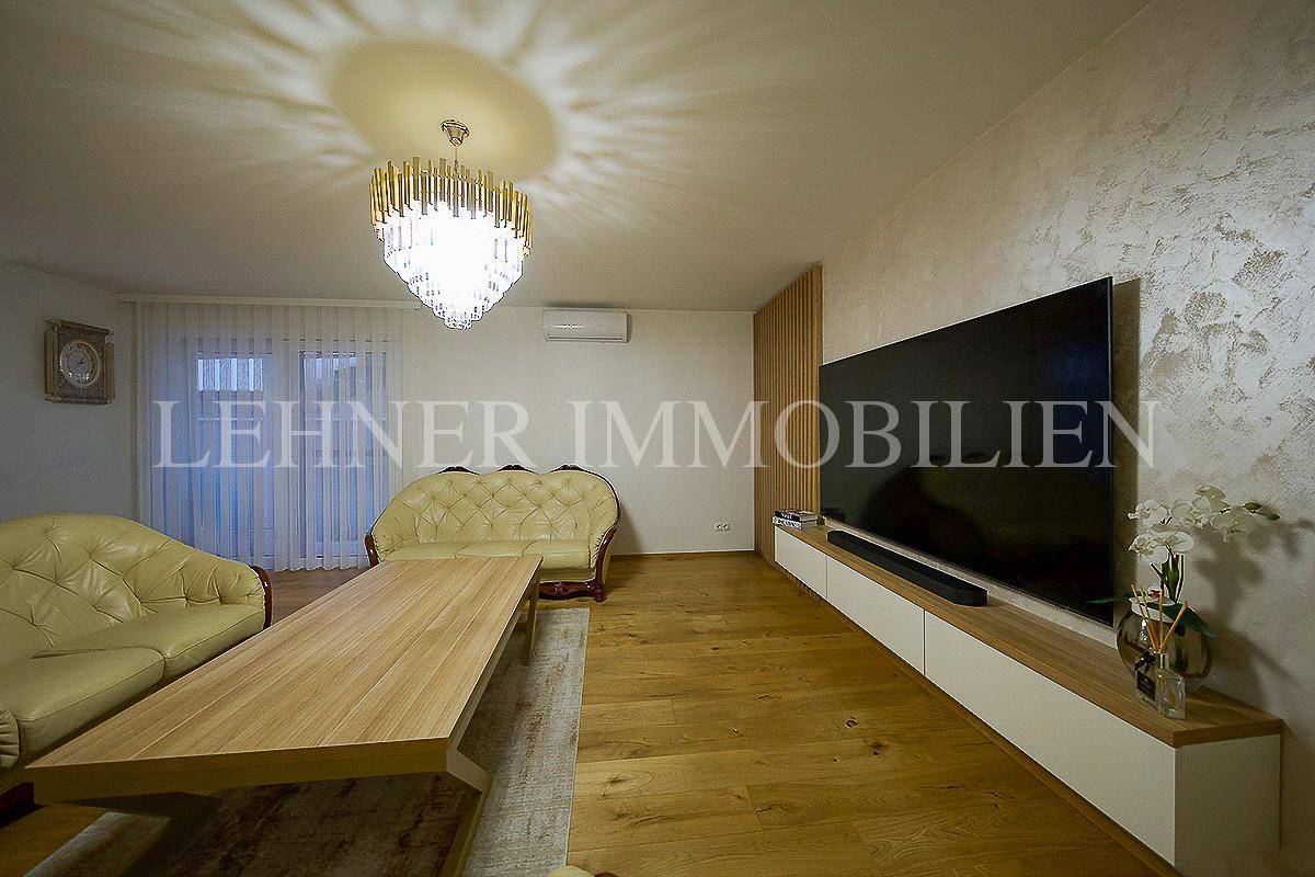 Stilvolles Wohnzimmer mit Holzboden, großem Fernseher und modernem Kronleuchter.