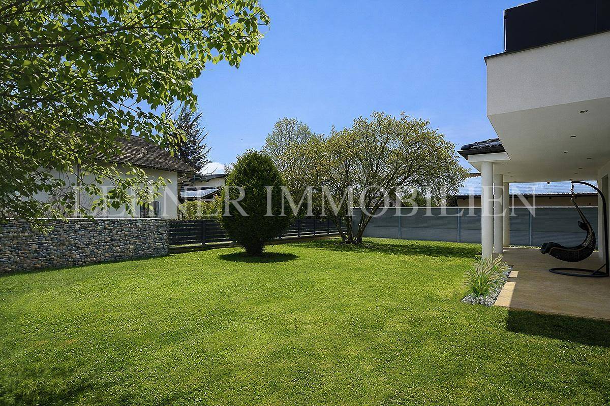 Weitläufiger grüner Garten mit Rasenfläche und Bäumen, angrenzend an die Terrasse.