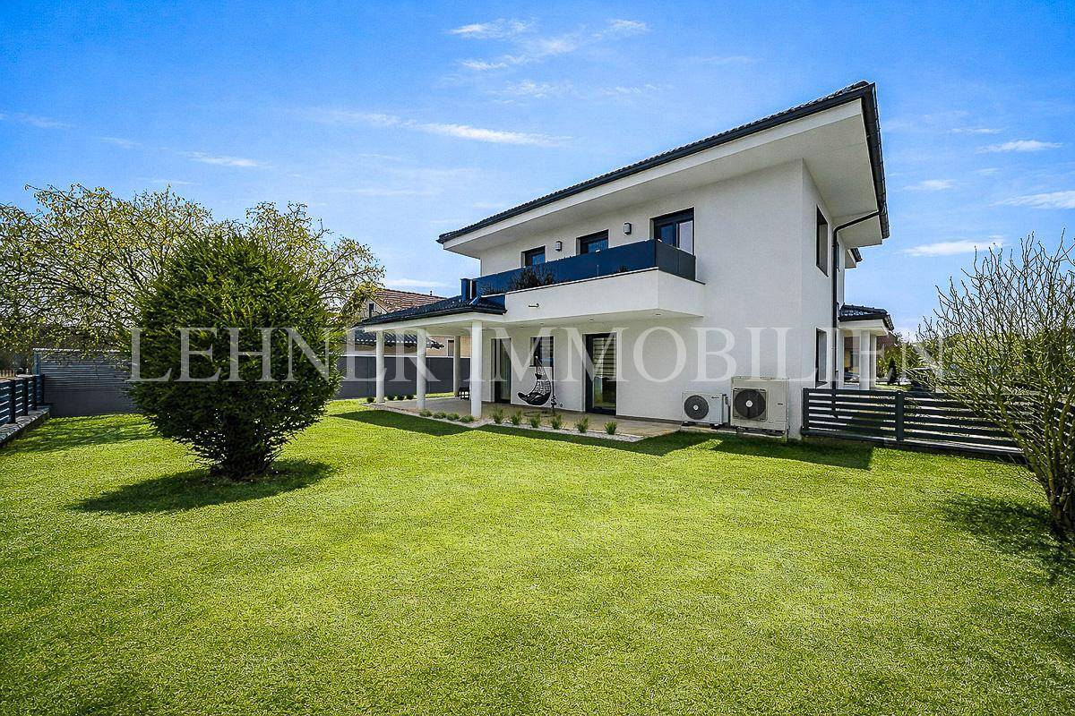 Großer gepflegter Garten mit Rasenfläche und überdachter Terrasse am modernen Haus.