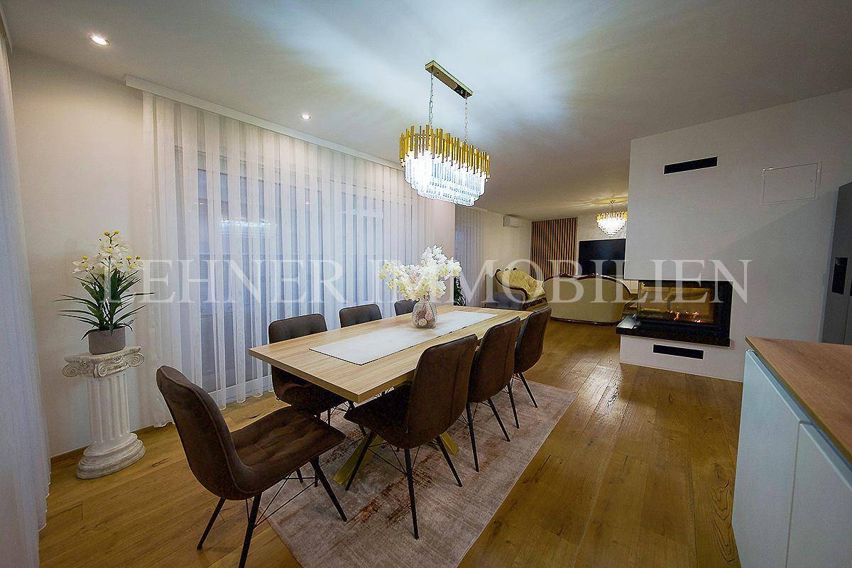 Essbereich mit elegantem Holztisch und Blick auf den Wohnbereich mit Kamin.