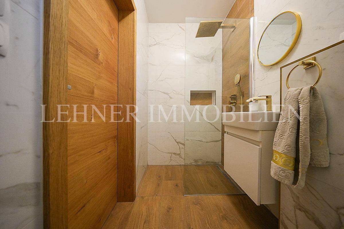 Modernes Badezimmer mit begehbarer Dusche, Marmorfliesen und eleganten Holzdetails.