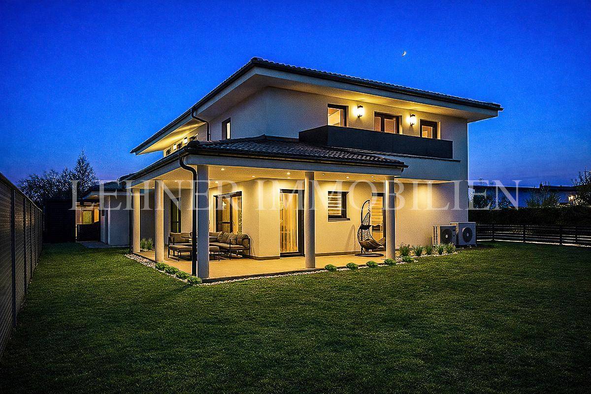 Überdachte Terrasse und Gartenbereich bei Nacht mit warmer Beleuchtung und Lounge-Möbeln.