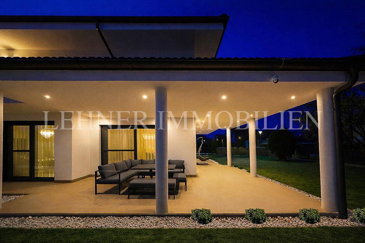 Gemütliche überdachte Terrasse bei Nacht mit indirekter Beleuchtung und Lounge-Möbeln.