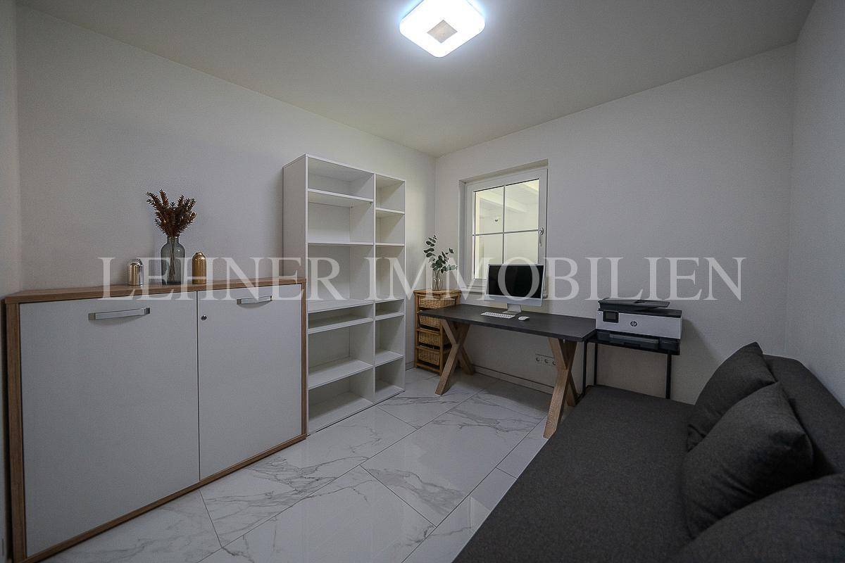 Modernes Büro mit Regalen, Schreibtisch und bequemer Couch für Gäste.