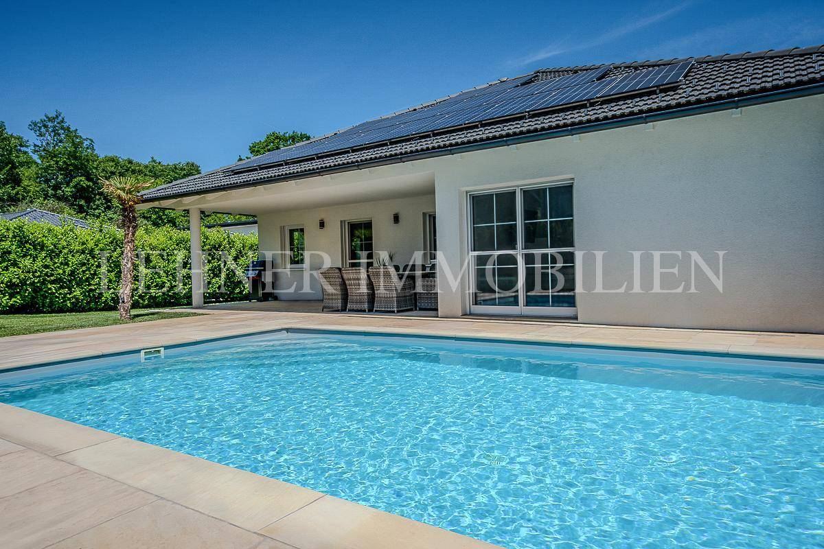 Außenansicht des modernen Hauses mit großem Poolbereich und sonniger Terrasse.