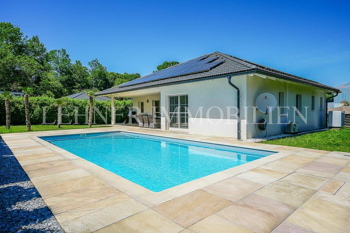 Weitläufiger Außenbereich mit rechteckigem Pool, gepflegtem Rasen und moderner Architektur.