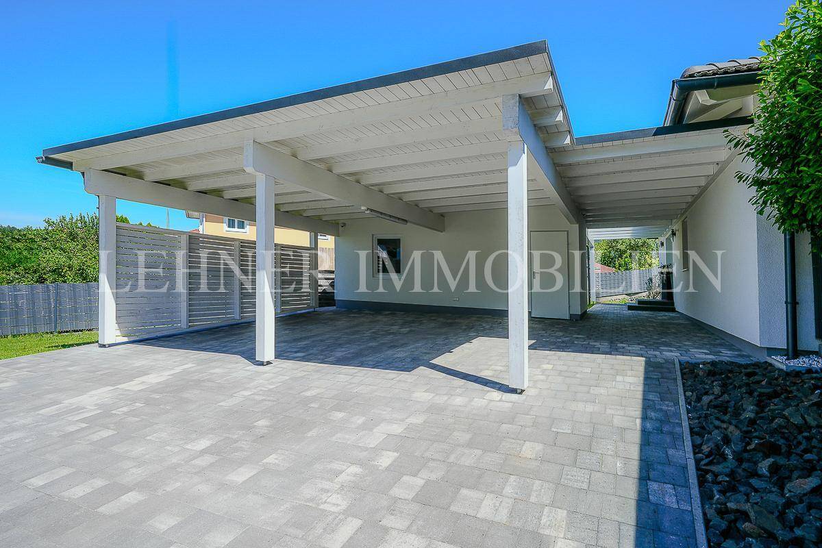 Überdachter Carport-Bereich mit gepflastertem Boden und Holzkonstruktion.