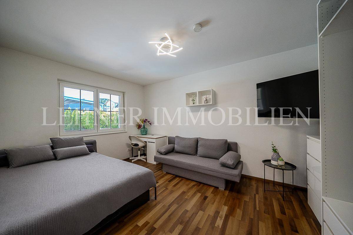 Helles Schlafzimmer mit Holzboden, Schlafsofa und Blick in den Garten.