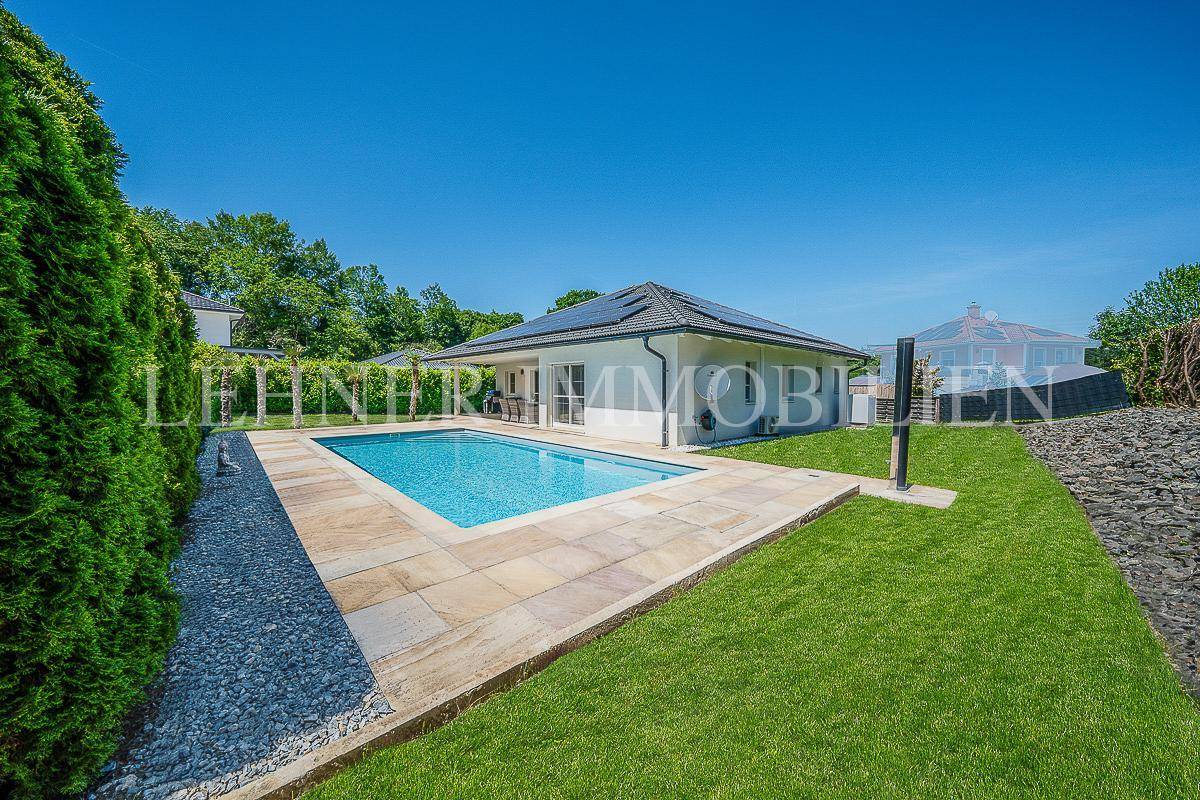 Seitliche Ansicht des Hauses mit Pool, Rasenfläche und umgebender Bepflanzung.
