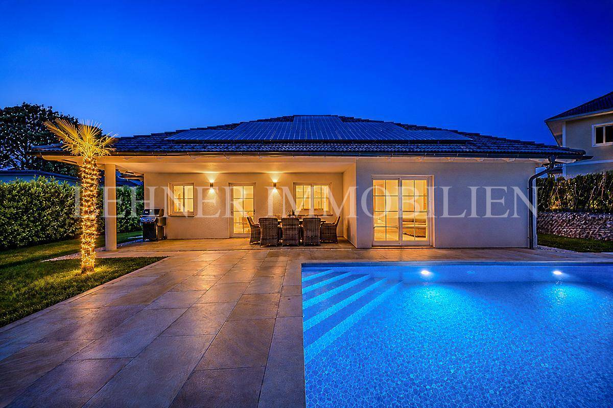 Stimmungsvolle Abendansicht des Hauses mit beleuchtetem Pool und gemütlicher Terrasse.