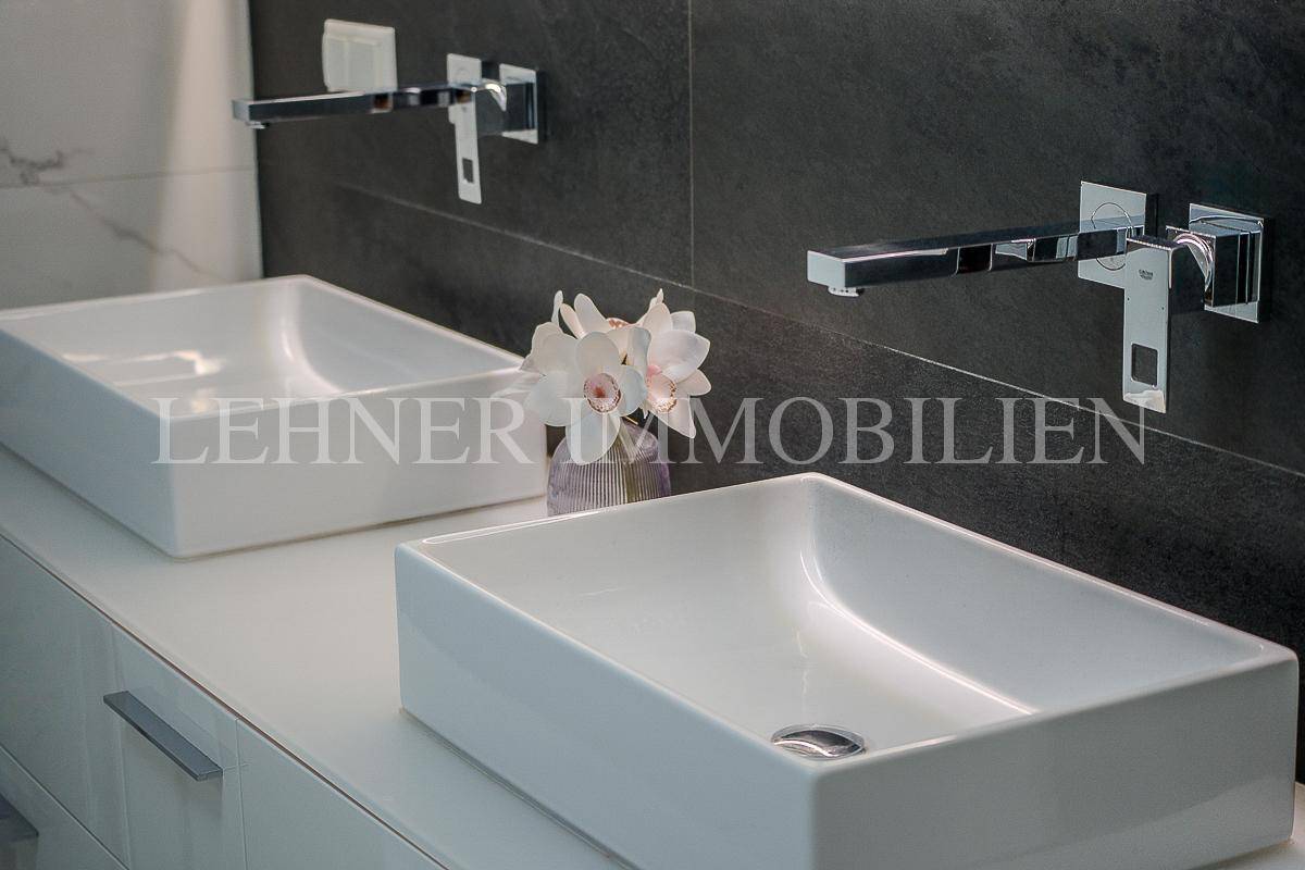 Detailaufnahme der modernen Doppelwaschbecken mit Wandarmaturen im Badezimmer.