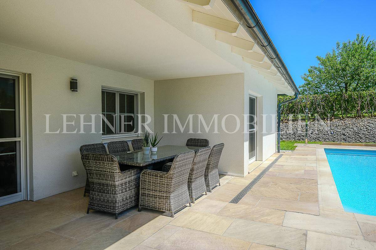 Überdachte Terrasse mit Rattan-Sitzgruppe und Esstisch, ideal für Mahlzeiten im Freien.