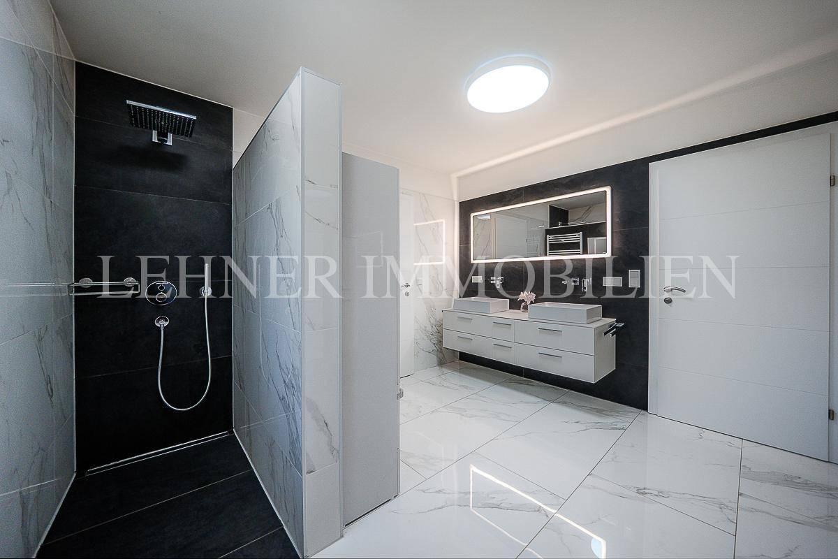 Elegantes Badezimmer mit großer begehbarer Dusche, Doppelwaschbecken und Marmorfliesen.
