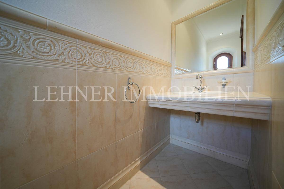 Gäste-WC mit elegantem Waschbecken, dekorativen Fliesen und einem kleinen Fenster.