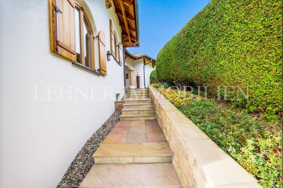 Elegante Steintreppe führt entlang einer Hecke zum Eingangsbereich des Hauses.