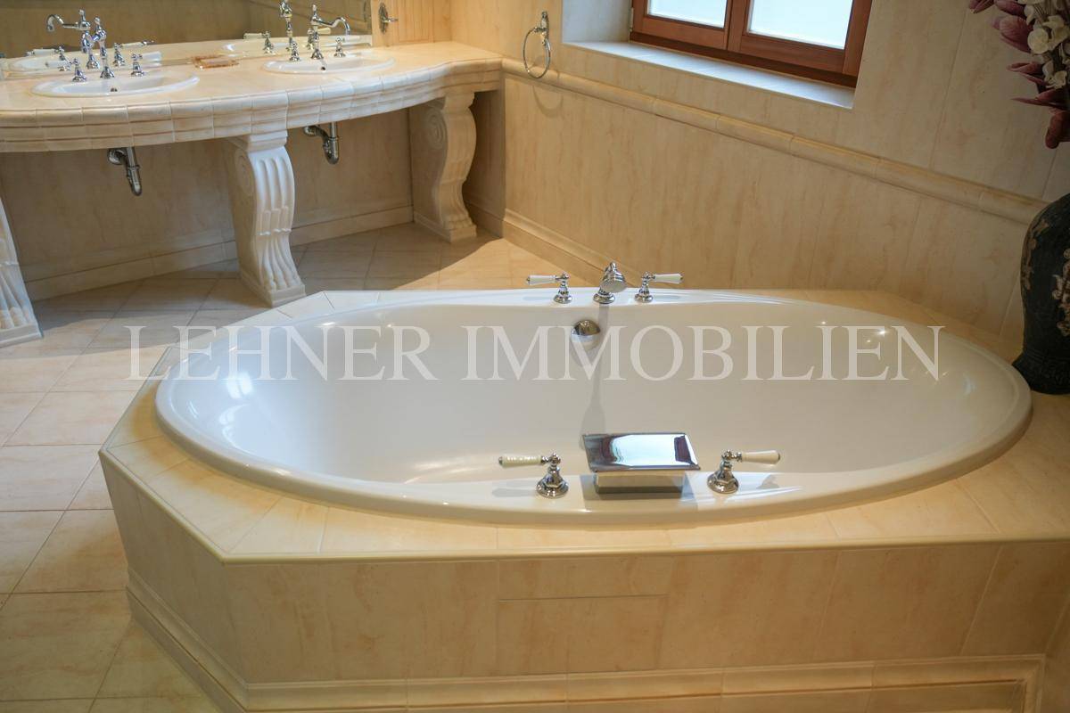 Große, eingelassene Badewanne mit klassischen Armaturen und umlaufender Ablagefläche.