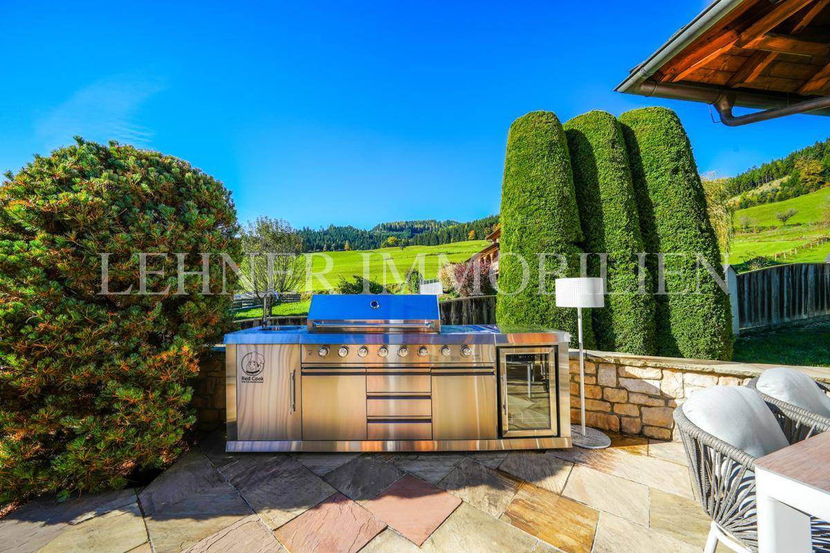 Hochwertige Edelstahl-Außenküche mit Grill und Kühlschrank auf der sonnigen Terrasse.